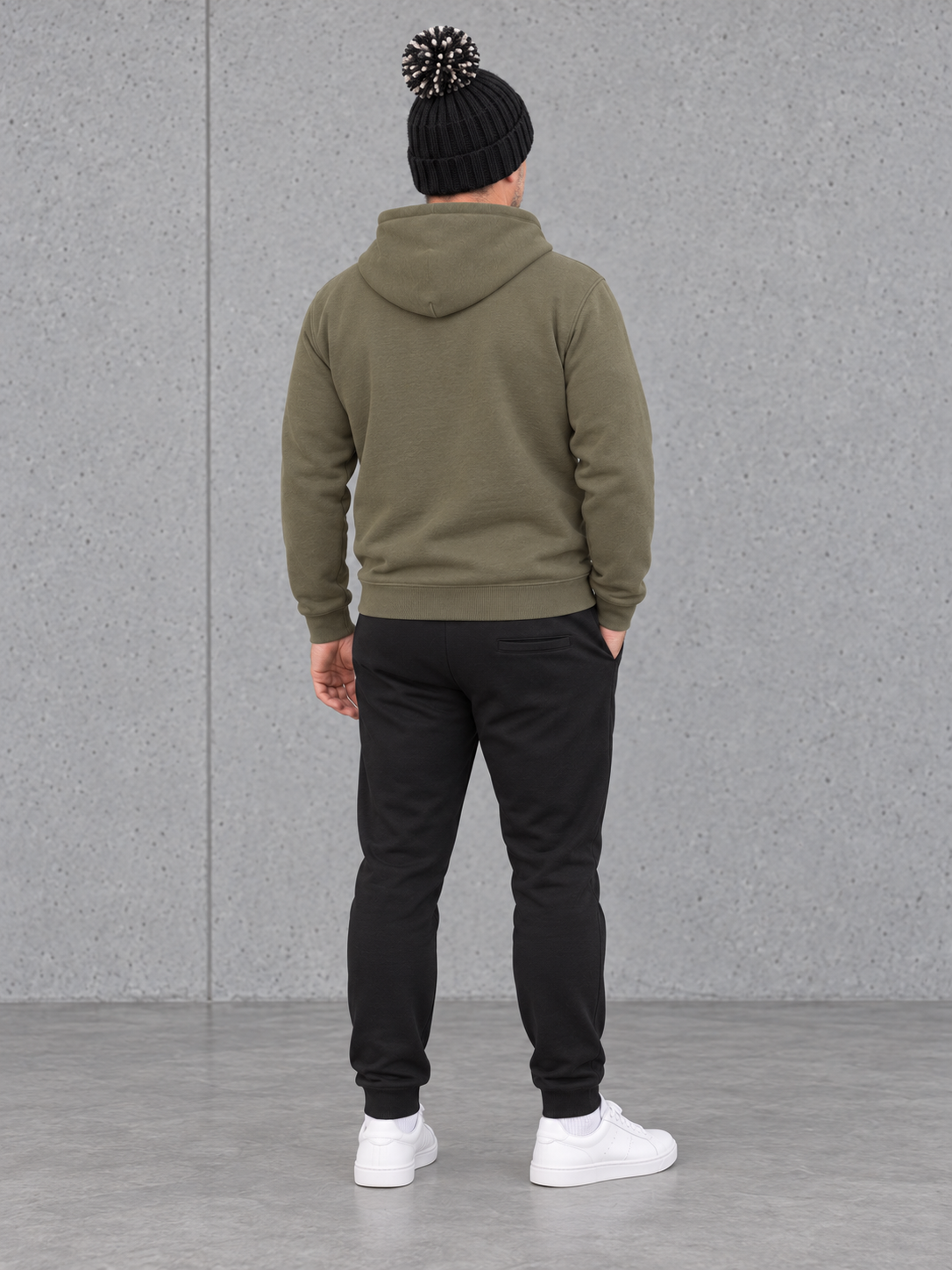 ESSENTIALS Sherpa Bommel Beanie in Black – Ganzkörper hinten, getragen von Olli mit Khaki-Hoodie