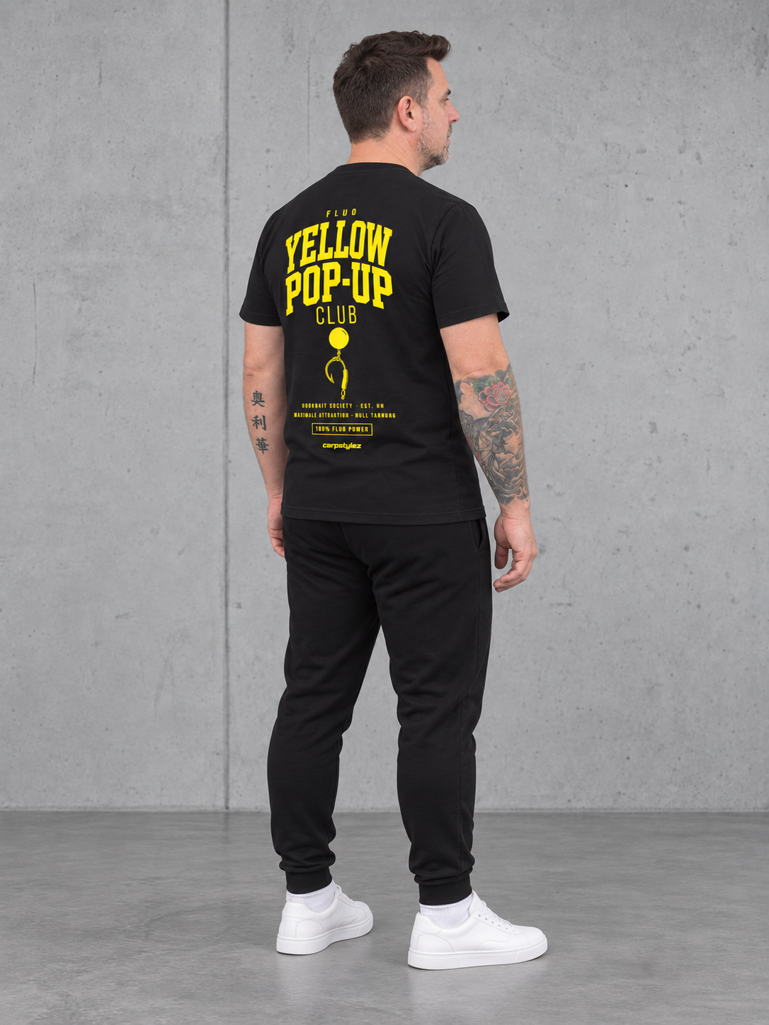 carpstylez Fluo Yellow Pop-Up Club – Olli trägt das schwarze Shirt, Ganzkörperansicht schräg von hinten #farbe_black