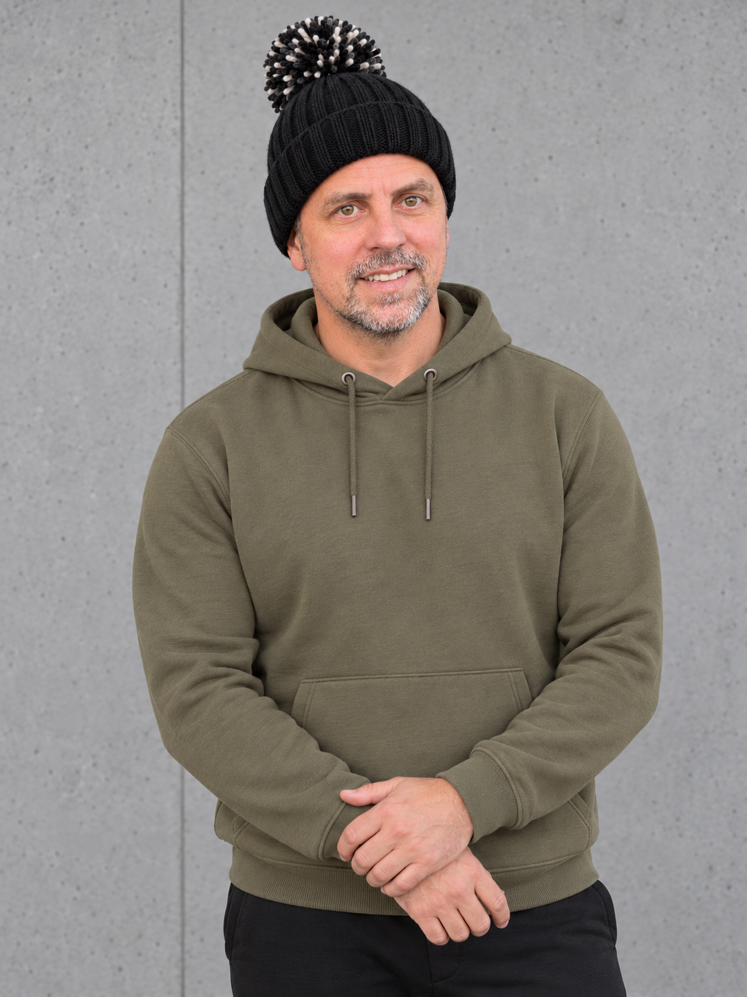ESSENTIALS Sherpa Bommel Beanie in Black – Frontansicht, getragen von Olli mit Khaki-Hoodie #color_black