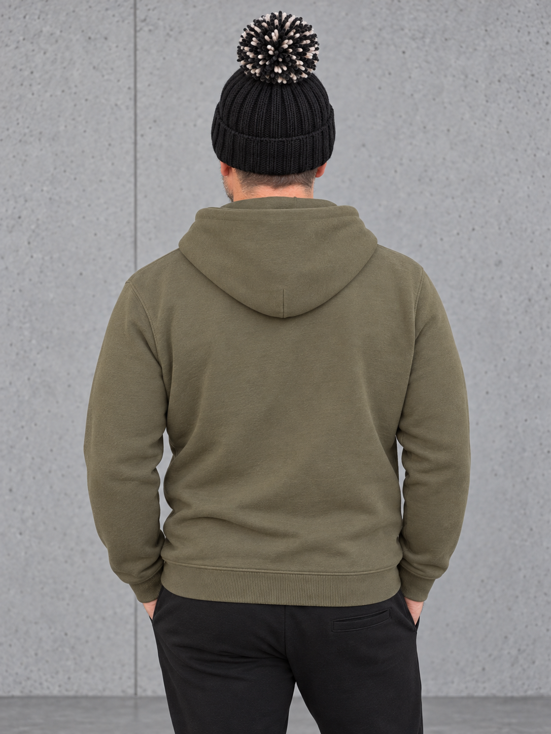 ESSENTIALS Sherpa Bommel Beanie in Black – Rückenansicht, getragen von Olli mit Khaki-Hoodie #color_black