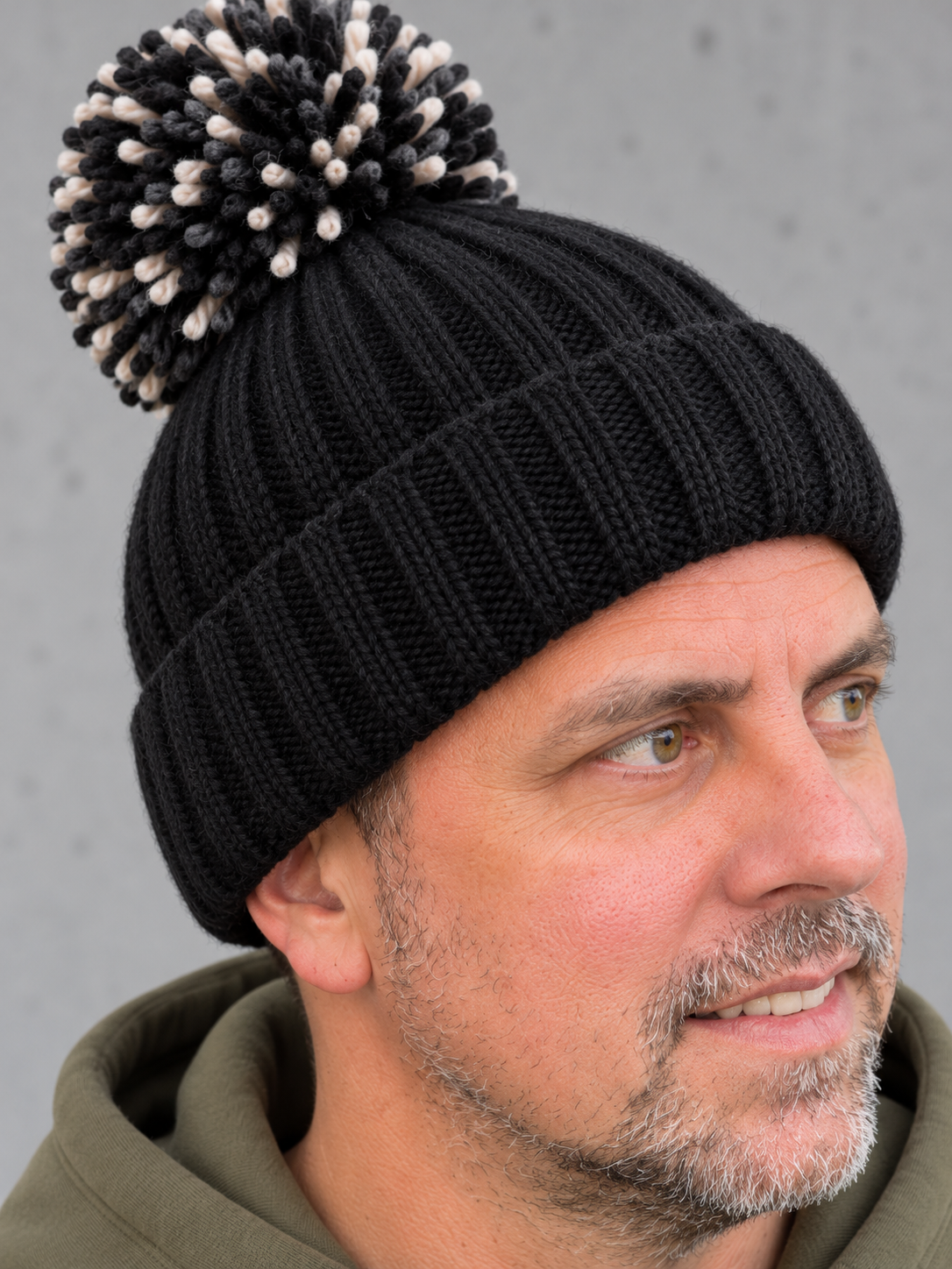 ESSENTIALS Sherpa Bommel Beanie in Black – Strickdetail, getragen von Olli mit Khaki-Hoodie #color_black, mustard