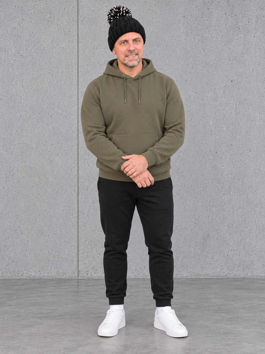 ESSENTIALS Sherpa Bommel Beanie in Black – Ganzkörper vorne, getragen von Olli mit Khaki-Hoodie