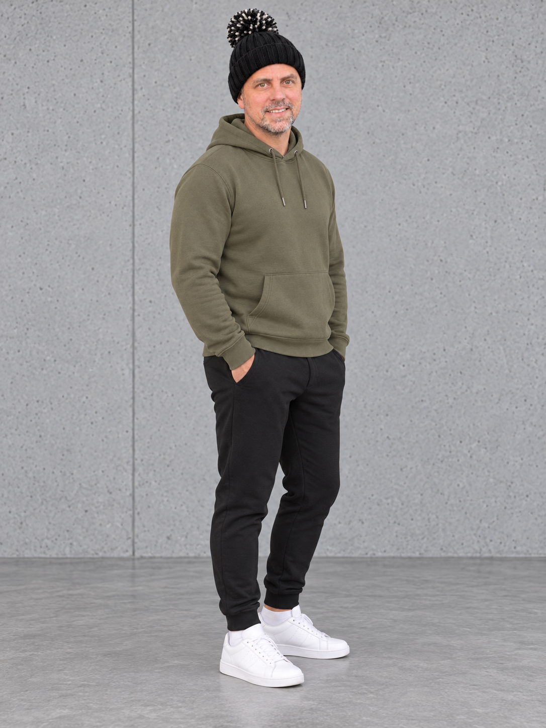 ESSENTIALS Sherpa Bommel Beanie in Black – Ganzkörper seitlich, getragen von Olli mit Khaki-Hoodie